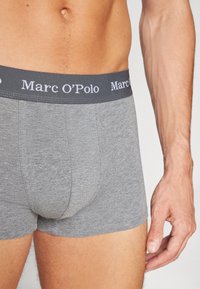 Boxer in grigio con una texture morbida, dotati di un elastico grigio scuro con il logo "Marc O'Polo" in bianco. Design aderente con una forma avvolgente.