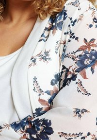 Kwiatowy kimono z kurtką z białym tłem i niebieskimi oraz brązowymi kwiatami. Lekki, przezroczysty materiał o miękkiej fakturze i otwartym fasonie.