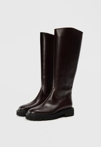 Bottes en cuir marron montantes, avec une finition lisse et un bout rond, intégrant une semelle en caoutchouc noire épaisse et des détails de couture minimalistes.