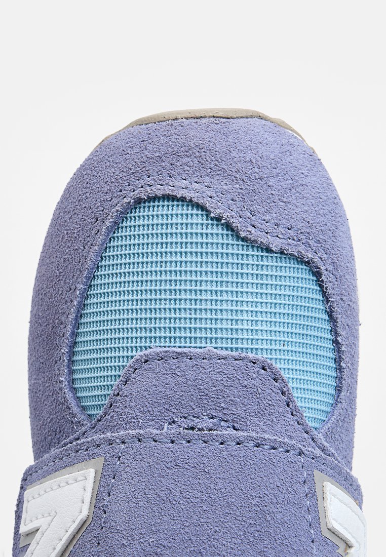 Hellblauer Sneaker mit einer strukturierten Wildleder-Oberfläche, blauen Mesh-Details und einem auffälligen grauen Logo-Akzent an der Seite.