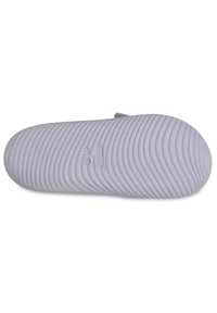 Suela de goma morada con surcos texturizados, con forma redondeada y logotipo en relieve. Ligera y diseñada para confort y tracción.