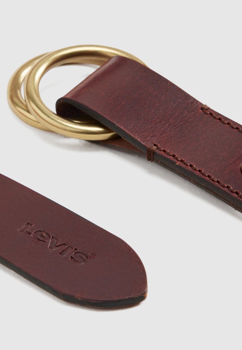 Portachiavi in pelle marrone scuro con due anelli in ottone e logo impresso a rilievo. Caratterizzato da una texture liscia e cuciture precise lungo il bordo.