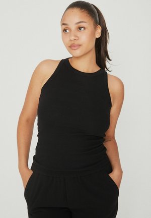 Schwarzes geripptes Tanktop mit hohem Ausschnitt und ärmellosem Design. Kombiniert mit schwarzen Hosen, die eine lockere Passform und seitliche Taschen bieten.
