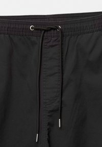Short de bain noir avec taille élastique et cordon noir noué à travers des œillets métalliques au centre avant.