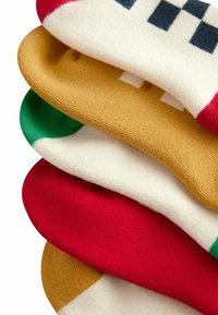 Gestapelte Socken in verschiedenen Farben: rot, grün, crème und gold. Weicher Stoff mit glatter Textur und einfachen geometrischen Mustern.