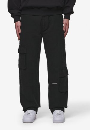 Black cargo pants with side pockets, straight legs, and a relaxed fit. Made of durable fabric, featuring a logo detail on the front.