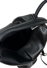 Černá kožená taška se zipovým uzávěrem, která se vyznačuje hladkou texturou a prostorným vnitřkem. Má zaoblený tvar a elegantní design.