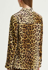 Camicia con stampa leopardata, collo a risvolto, maniche lunghe, tessuto liscio e una vibrante miscela di marroni e oro.