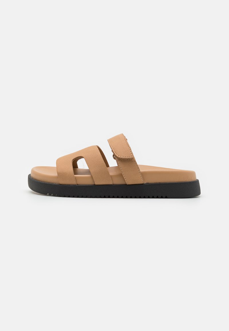 Bruna slidesandaler med två breda remmar och ett kardborrestängning, en dämpad fotbädd och en svart texturerad sula.