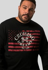 Svart långärmad tröja med en sliten grafik som visar en röd amerikansk flagga, texten "CRUISING DREAMS AUSTIN" och dubbla kolvikoner.