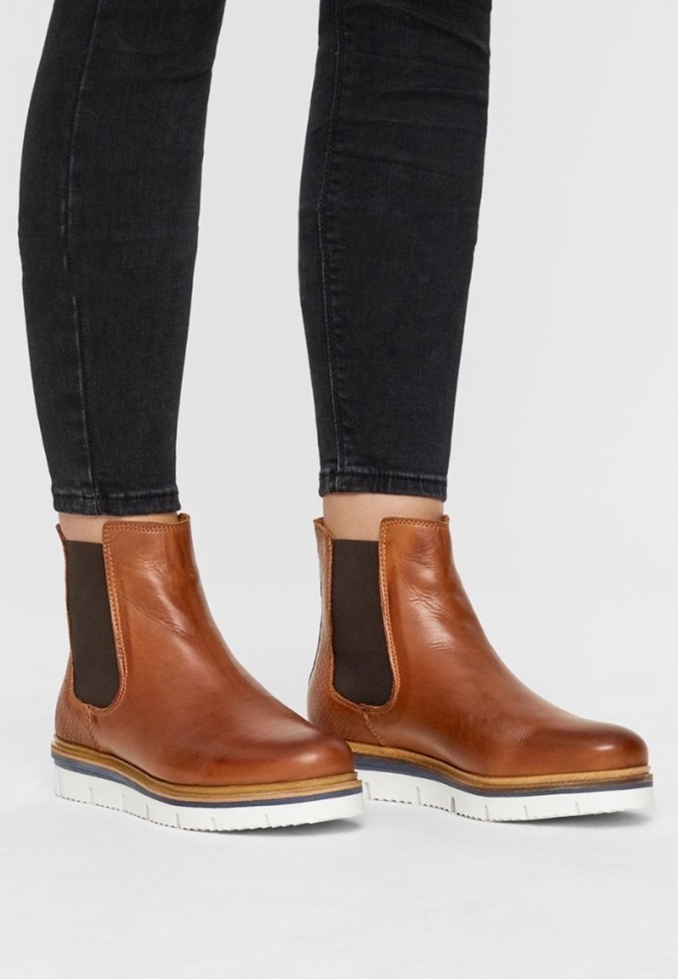 Brown leather ankle boots with elastic side panels, white rubber soles, and a smooth finish. Features a sleek, rounded toe design.