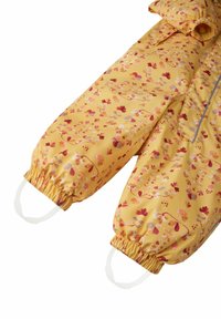 Voděodolný žlutý snowsuit s květinovým vzorem v červených a růžových odstínech, s elastickými manžetami a smyčkami na palce pro bezpečné uchycení.