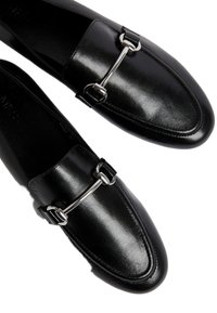 Svarta läderloafers med en silverfärgad spänne, elegant rundad form med slät yta och sydda detaljer.