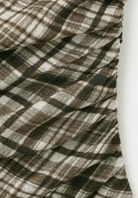 Tissu à carreaux marron et beige avec des lignes diagonales et horizontales créant un motif à carreaux et une texture douce.