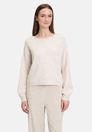Maglione di knitted color beige chiaro con scollatura rotonda e maniche lunghe, leggermente morbide, abbinato a pantaloni beige a coste coordinati.