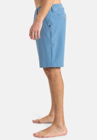 Pantalones cortos azul claro hechos de una tela suave, de largo hasta la rodilla, con bolsillos laterales y traseros, y un frente plano con un cierre de botón único.