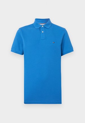 Polo bleu en coton, doté d'un col à revers, de manches courtes et d'un petit logo sur la poitrine gauche. Couleur unie sans motifs.