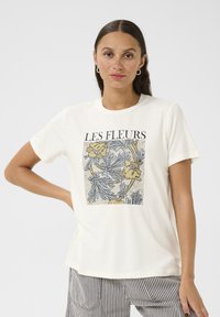 T-shirt crème à manches courtes avec un imprimé floral aux accents jaunes et bleus. Encolure ronde et coupe décontractée.