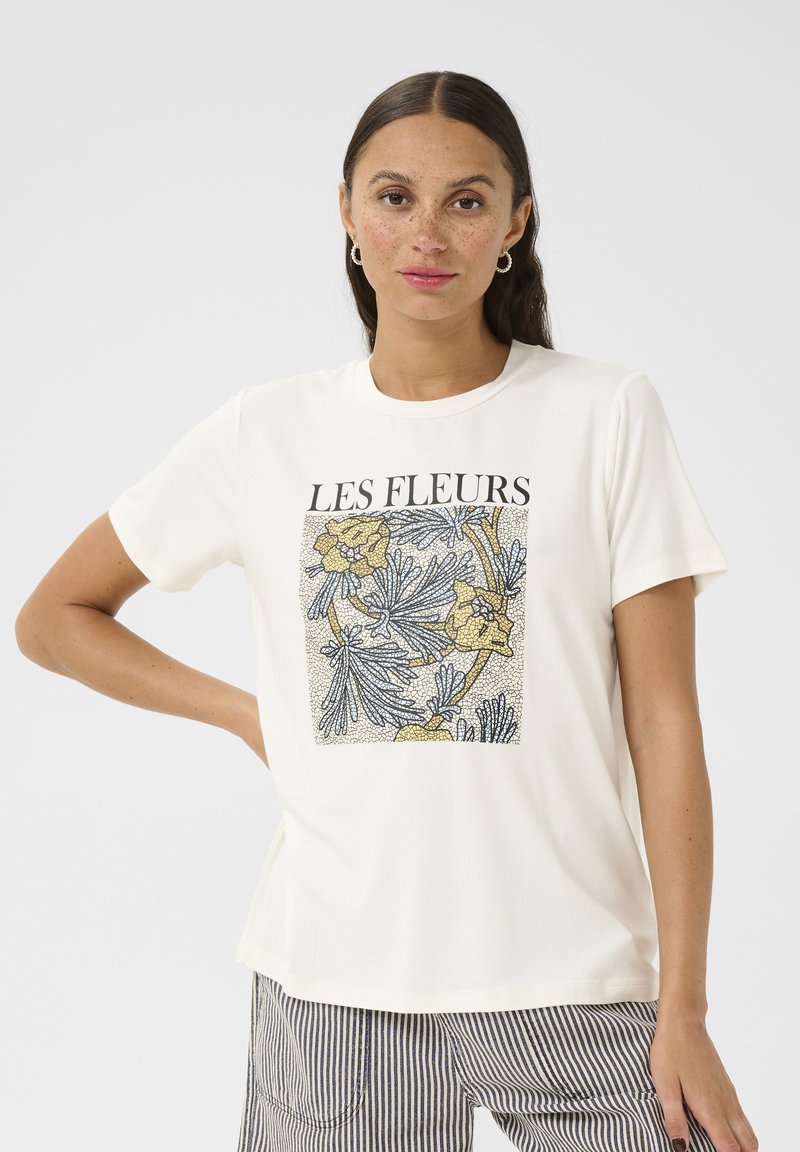 T-shirt crème à manches courtes avec un imprimé floral aux accents jaunes et bleus. Encolure ronde et coupe décontractée.