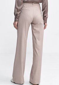 Beżowe spodnie w paski z wysokim stanem i szerokimi nogawkami. Wykonane z gładkiego materiału, z dwiema tylnymi kieszeniami i dopasowanym krojem.