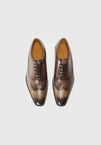 Scarpe da uomo in pelle marrone con un effetto degradé che va dal scuro al chiaro, caratterizzate da dettagli perforati e una punta appuntita.
