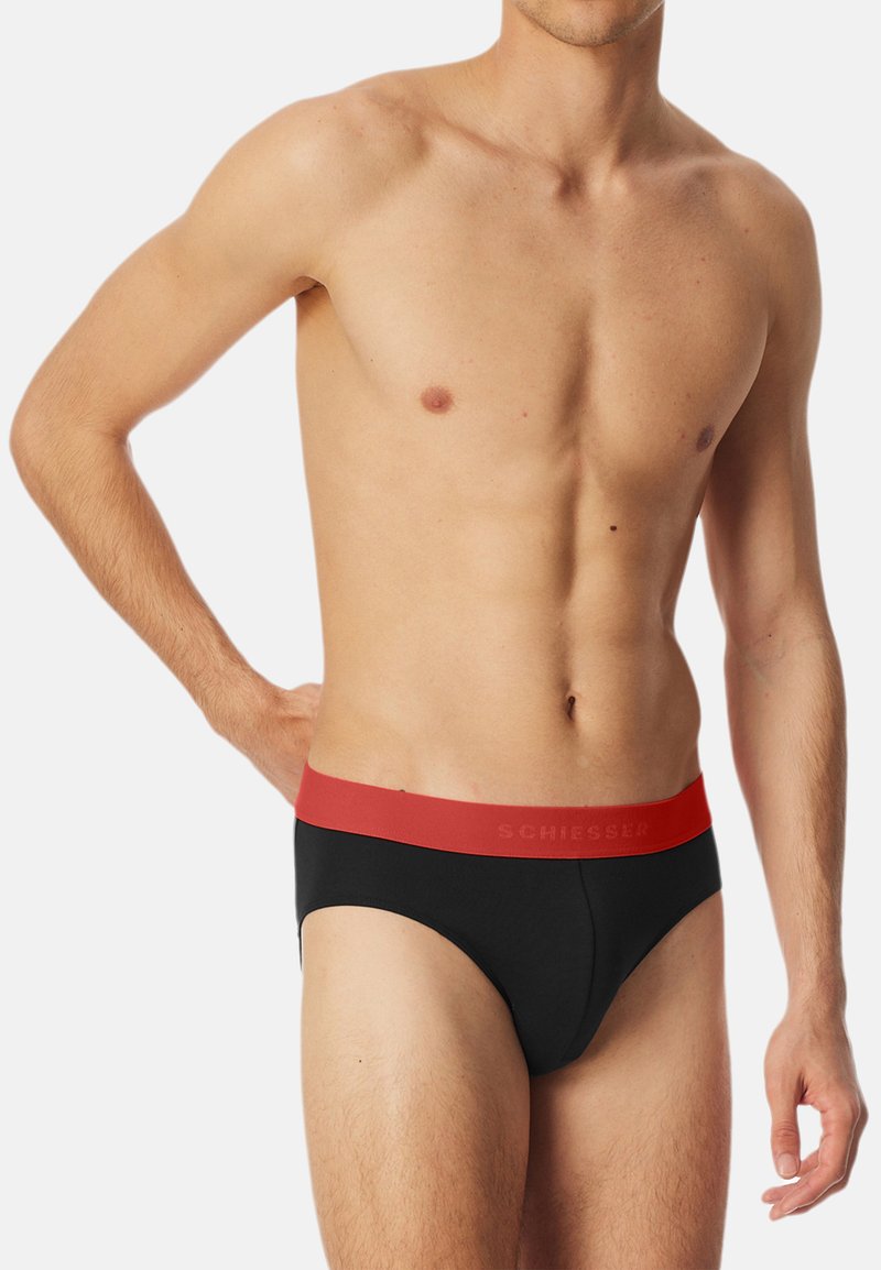 Sorte briefs med en rød elastik, der har brandnavnet. Glat stof med en tætsiddende design og klassisk brief-snit.