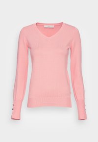 Pull à manches longues en V rose clair avec des poignets et un ourlet côtelés, petits boutons décoratifs sur les manches et logo "GUESS" subtil près de l'ourlet.