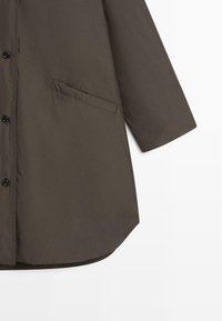 Dark brown, lightweight coat featuring a button closure, long sleeves, and a side pocket, with a smooth texture and curved hemline.