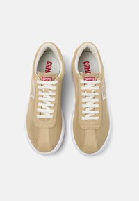 Beige leather sneakers with white laces and rubber soles. Features a red "CAMper" tag and subtle stitching accents on the upper.