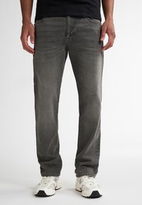 Jeansi din denim gri cu o croială dreaptă, design cu cinci buzunare, estompare subtilă și cusături în contrast, asortați cu adidași albi.