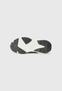 Black and white sneaker sole with textured rubber grip patterns, labeled "GUESS," featuring a smooth off-white midsole.