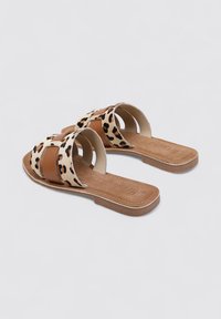 Chanclas con estampado de leopardo, tiras de cuero en color marrón, suelas planas y un interior suave. Diseño de punta abierta con tiras cruzadas para mayor ventilación.