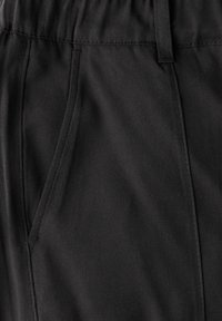 Schwarze Stoffhosen aus einem glatten Material, mit elastischem Bund und seitlichen Taschen, die eine saubere Nähte aufweisen.