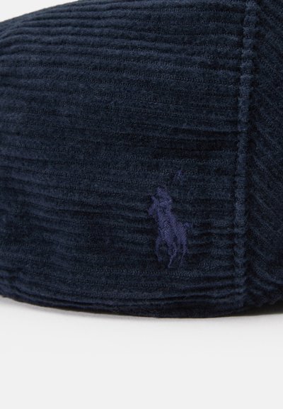 Námornícka kordurová čiapka s ryhovanou textúrou, s malým vyšitým logom v tmavšom odtieni. Guľatý tvar s prešitými detailmi.