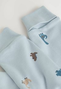 Helle blaue Baumwollsocken mit gerippten Bündchen, die kleine Dinosaurier- und Handabdrücke in braunen, blauen und beigen Mustern zeigen.