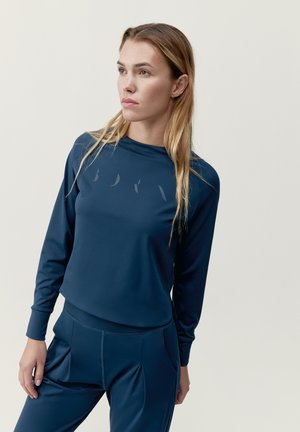 Marineblauw sportieve longsleeve met een ronde halslijn, zachte stof, subtiele logo aan de voorkant, gecombineerd met bijpassende broek met plooien.