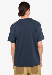 Marineblauwe katoenen T-shirt met een ronde halslijn en korte mouwen, heeft een eenvoudige achterkant en een ontspannen pasvorm. Minimalistische branding zichtbaar.