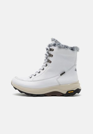 Bottes blanches en cuir à la cheville avec bordure en fausse fourrure, œillets métalliques et semelle épaisse Vibram. Le côté présente une étiquette logo ; surfaces lisses et texturées.