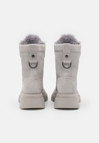 Gray suede ankle boots with a soft gray faux fur lining, round toe, and a thick rubber sole. Features a fabric loop and metal accent on the heel.