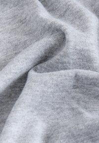 Szürke pamutszövet, lágy tapintású és sima felületű. Az anyag finom tónusváltozásokat és szabályos kötésmintázatot mutat.