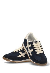 Zapatillas deportivas azul marino con cordones crema y acentos a rayas. Presentan una parte superior de gamuza y malla, suela de goma y diseño de punta redonda.