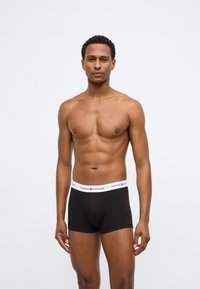 Boxer briefs neri in cotone con elastico bianco riportante il logo "TOMMY HILFIGER", dalla texture liscia, design attillato e lunghezza a metà coscia.