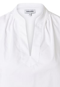 Weiße Bluse mit V-Ausschnitt, gerafften Details an den Schultern und einem Etikett mit der Aufschrift "MORE & MORE", Größe 36. Glatte Baumwoll-Struktur.