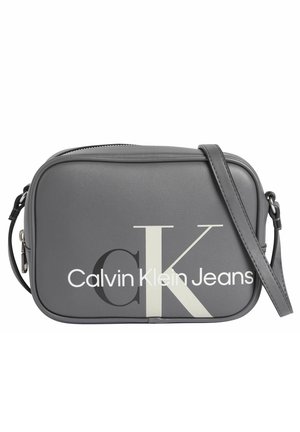 Graue rechteckige Umhängetasche mit verstellbarem Riemen, mit großem überlappendem „CK“ und „Calvin Klein Jeans“ Logo vorne.