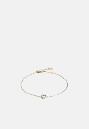 Bracelet en chaîne dorée avec un accent en argent en forme de cœur, comportant une pierre précieuse transparente au centre. Fermé par un fermoir de type lobster.