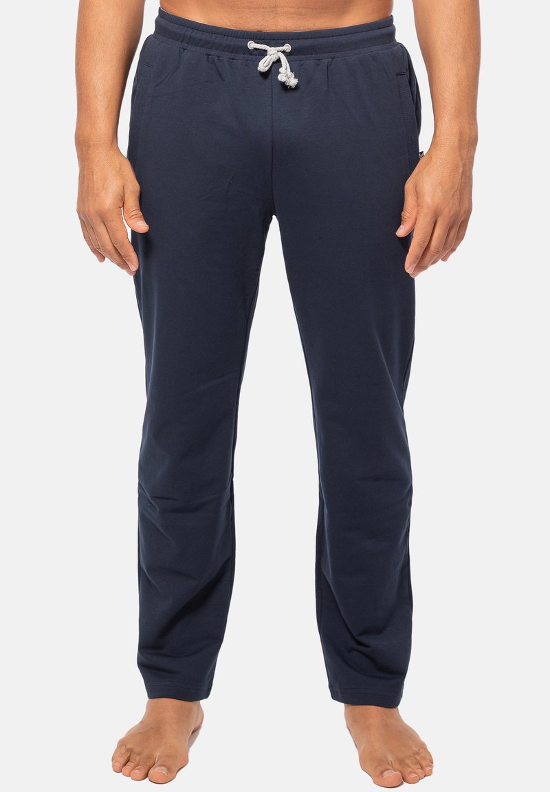 Navyblauwe trainingsbroek van katoen, voorzien van een elastische tailleband met een trekkoord en twee zijzakken. Glad textuur en rechte snit.