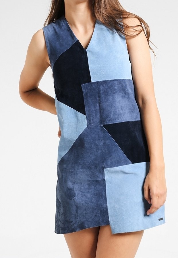 Patchwork sukně z semiše v modré a námořnické barvě s véčkovým výstřihem, obsahující různé odstíny a textury, a s kapsou vpředu.