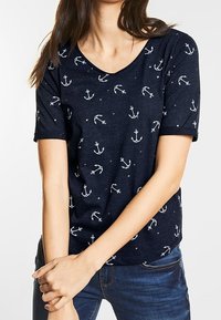 Marinblå t-shirt med kort ärm som har en V-halsdesign och vita ankarmönster samt små stjärnor över hela tyget. Avslappnad passform.