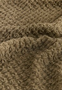 Strukturierter Stoff in einem olivgrünen Farbton, der ein erhabenes, gekräuseltes Muster aufweist, um visuelles Interesse und taktile Variation zu bieten.