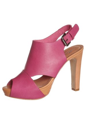 Fuksjowe skórzane sandały na wysokim obcasie z otwartym palcem, krzyżowym designem, regulowanym paskiem przy kostce i jasnobrązową platformą.